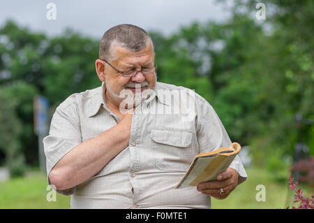 Outdoor portrait of senior man reading an interesting book Stock Photo