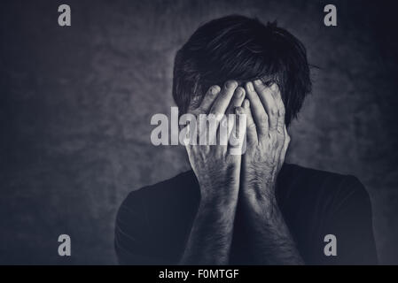 Grief, man covering face and crying, monochromatic image Stock Photo
