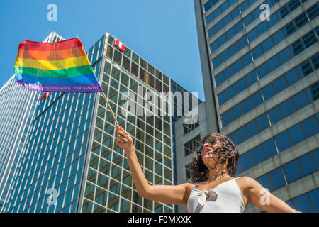 MONTREAL, CANADA, 16th August 2015. A female spectator is waving the gay rainbow flag at the 2015 Gay Pride Parade in Montreal. © Marc Bruxelle/Alamy Live News