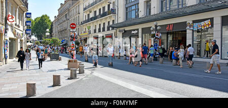 People in shade side of Rue de la République shopping street at the time of the annual July arts festival in very hot sunny weather Avignon Provence Stock Photo