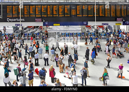 View from above commuters on busy Waterloo train station concourse with departure board and platform entry exit ticket barriers London England UK Stock Photo