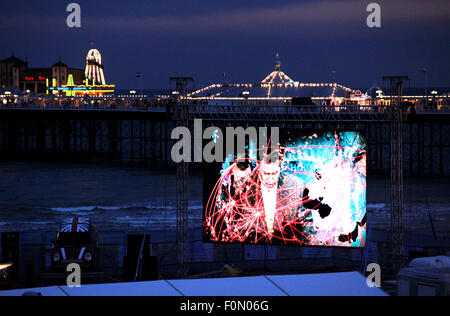 Brighton, UK. 18th August, 2015. The Brighton Big Screen cinema showing Dawn of the Planet of the Apes  with the pier lit up behind at sunset this evening . The screen is the largest beachfront cinema in the UK and is showing 93 films over the next month  Credit:  Simon Dack/Alamy Live News Stock Photo