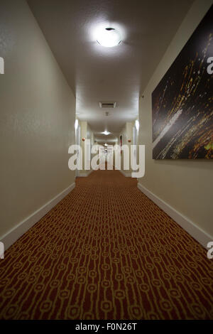 Very long hall way in a hotel in Reno, straight line with red carpet going to the escalator section. Stock Photo