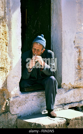 Turkish man sitting in the entrance to his house and smoking a cigarette Stock Photo