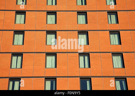 Facade of a brick office building with successive rows and floors of tinted glass windows. Stock Photo