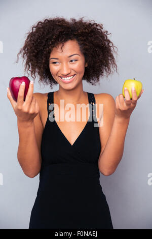 Portrait of a smiling african woman holding apples over gray background Stock Photo