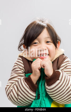 Cute Asian girl shivering in coat, studio isolated white background. Stock Photo