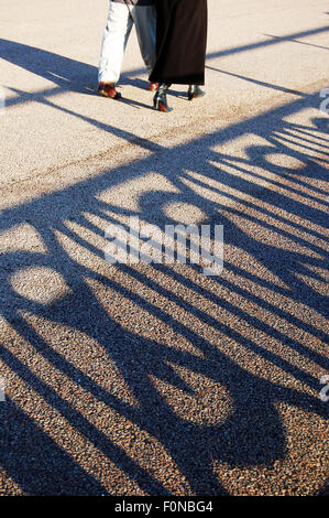 Two people walking on Hove promenade in bright sunshine Stock Photo - Alamy