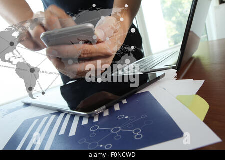 business documents on office table with texture the world on digital tablet and man using smart phone in the background Stock Photo