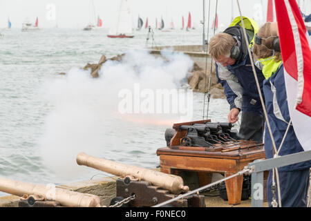 A man starts a yacht race with the cannon starting guns at Cowes Week yacht racing on the Isle of Wight 2015 with flames coming Stock Photo
