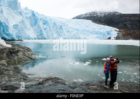 Young couple taking a selfie in front of Brujo Glacier Asia Fjord Patagonia Chile Stock Photo