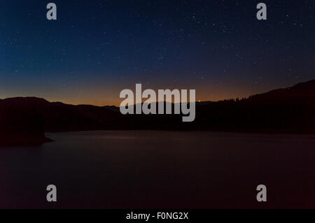 stars moving in night sky over mountain lake Stock Photo