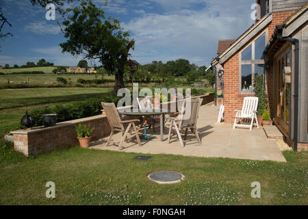 Empty teak chairs and table on patio of new ecohouse UK Stock Photo