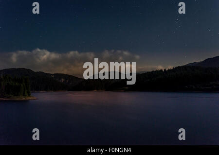 stars moving in night sky over mountain lake Stock Photo