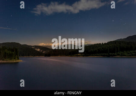 stars moving in night sky over mountain lake Stock Photo