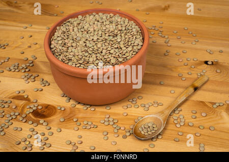 Green lentils in a pot with a wooden spoon on a wooden surface Stock Photo