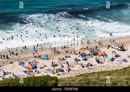 A busy afternoon on Sennen Beach in Cornwall. Sunbathers, surfers and body boarders all enjoy the sunshine and waves at this pop Stock Photo