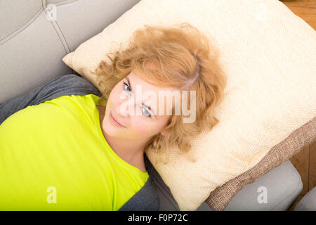 A young, plus size woman relaxing on the sofa. Stock Photo