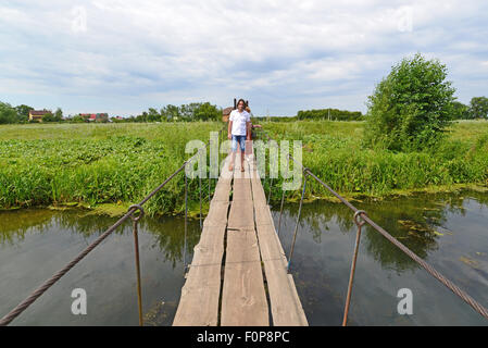 two people go on a suspension bridge over the river Stock Photo