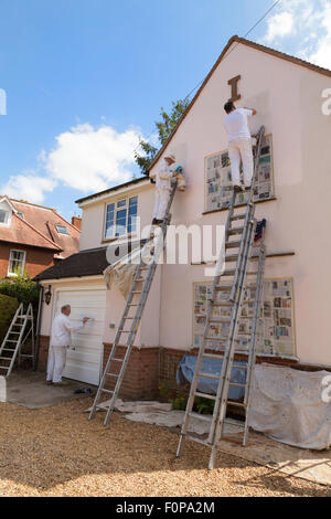 Professional house painters painting the exterior of a house, Suffolk, East Anglia, England UK