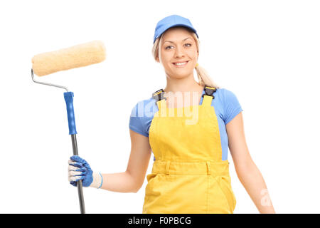 Young female house painter in a yellow overall holding a paint roller isolated on white background Stock Photo