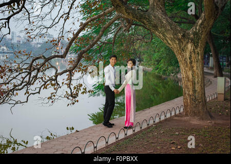 Romantic asian couple, a young Vietnamese couple holding hands pose for a photo alongside Hoan Kiem Lake in Hanoi, Vietnam. Stock Photo