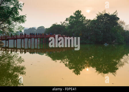 Hanoi lake bridge, view at sunset of tourists crossing the Huc Bridge on Hoan Kiem Lake to visit the Temple Of The Jade Mound, Vietnam Stock Photo