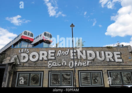 Let's Adore and Endure Each Other graffiti on wall with train carriages on a roof Great Eastern Street in Shoreditch East London UK  KATHY DEWITT Stock Photo
