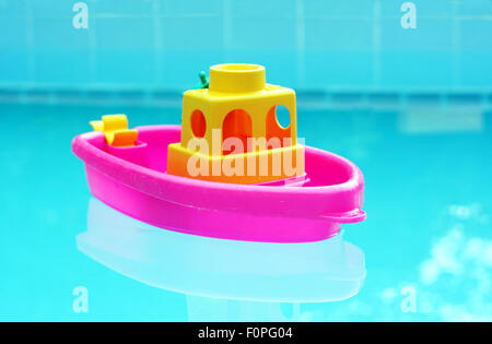 Small toy plastic boat floating in a swimming pool Stock Photo