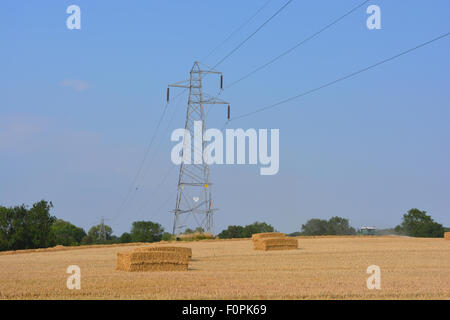 Electricity pylon in a stubble field with bales of  hay, North Yorkshire, England. Stock Photo