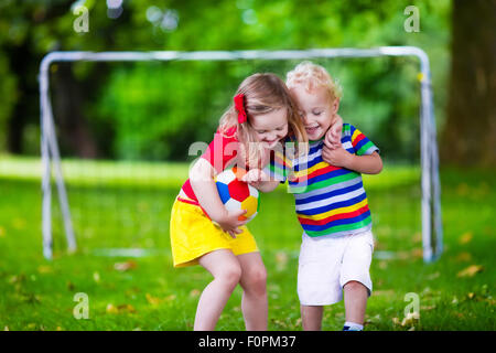 Two happy children playing European football outdoors in school yard. Kids play soccer. Active sport for preschool child Stock Photo