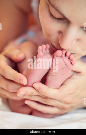 Closeup of mother holding and kissing newborn's feet Stock Photo