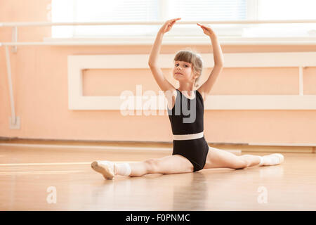 Young girl doing splits while warming up at ballet dance class Stock Photo
