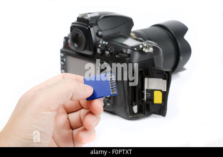 Hand holds SD Memory card - Flash card and DSLR camera on the background Stock Photo