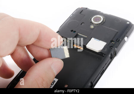 Human hand inserting Micro SD card into cell phone (smartphone) Stock Photo