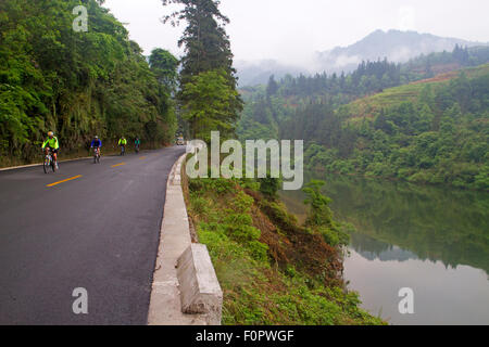 Group of cyclists riding beside a river in Guizhou province Stock Photo