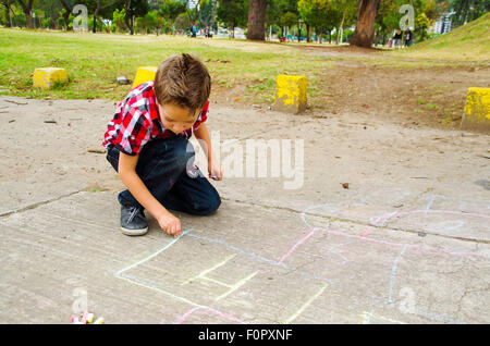 Sweet boy drawing playing hopscotch Stock Photo