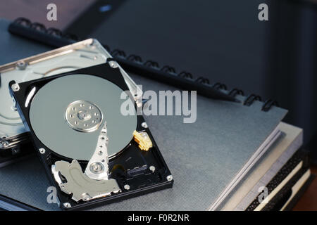Close up of open computer hard disk drive with social network diagram on desk and notebook Stock Photo
