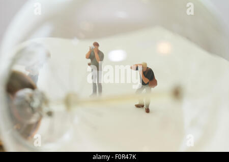 Creative idea concept - miniature photographer with vintage light bulb on open paper notebook Stock Photo