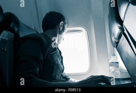 Mature man sitting in window seat on airplane. Stock Photo
