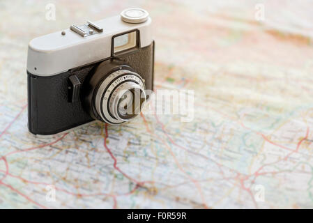 35mm vintage photocamera on travel map in sunlight Stock Photo