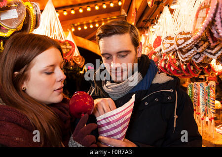 couple eating sweets on christmas market Stock Photo