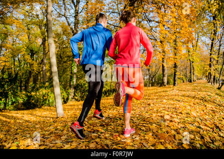 Running together - young couple jogging in autumn park, rear view Stock Photo