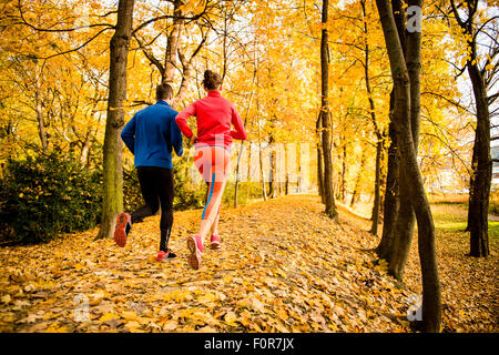 Running together - young couple jogging in autumn park, rear view Stock Photo