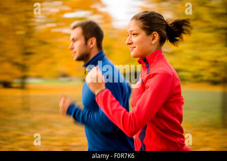 Panning photo of young couple jogging together in nature Stock Photo