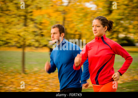 Panning photo of young couple jogging together in nature Stock Photo