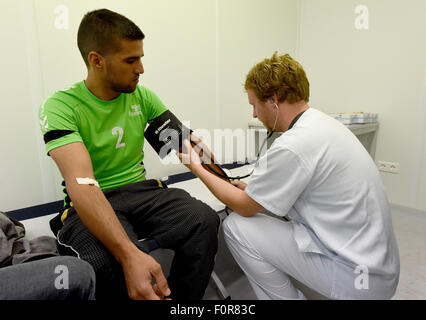 Rendsburg, Germany. 20th Aug, 2015. Doctor Alexander Humberg (R) from Luebeck looks at a refugee from Iraq in the primary health care centre that is currently placed in containers in Rendsburg, Germany, 20 August 2015. More than 60 doctors and nurses from the university hospitals in Kiel and Luebeck started their voluntary service to take care of the refugees in the new reception centre. Photo: CARSTEN REHDER/dpa/Alamy Live News Stock Photo