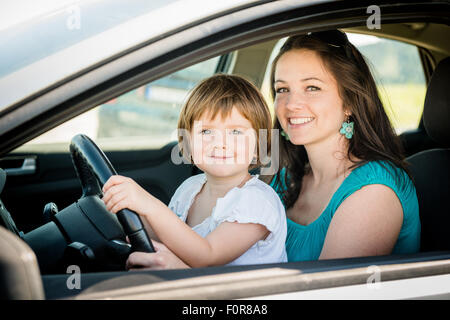 Portrait of mother and child pretend driving car sitting both on front driver seat Stock Photo