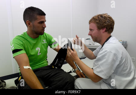 Rendsburg, Germany. 20th Aug, 2015. Doctor Alexander Humberg (R) from Luebeck looks at a refugee from Iraq in the primary health care centre that is currently placed in containers in Rendsburg, Germany, 20 August 2015. More than 60 doctors and nurses from the university hospitals in Kiel and Luebeck started their voluntary service to take care of the refugees in the new reception centre. Photo: CARSTEN REHDER/dpa/Alamy Live News Stock Photo