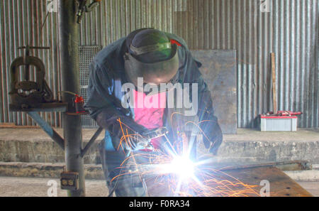 Man welding a piece of iron on a work table in a shop Stock Photo